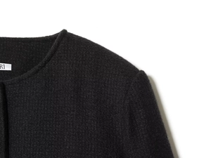 Close-up of black wool fabric texture and neckline detail on a slim-fit blazer jacket
