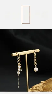 Detailed shot of asymmetric gold earrings featuring natural pearls and long tassel chains