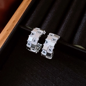 Vue détaillée de créoles argentées avec zircons carrés sur boîte en velours noir