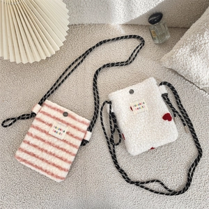 Detail of plush crossbody bags with pink stripes, red hearts, and woven shoulder straps