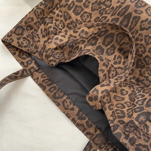 Close-up of leopard print canvas texture and reinforced stitching on a shoulder bag
