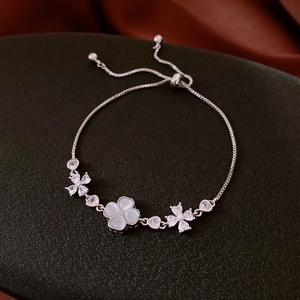 Detail of adjustable flower bracelet with opal clover and rhinestone heart charms