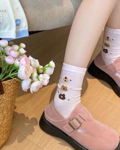 Close-up of pink mid-calf socks with cute bear pattern worn by a model in soft light