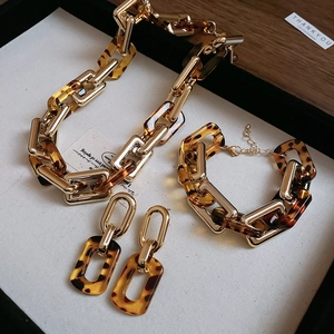 Dettaglio del set di gioielli con resina leopardata e catena dorata su vassoio nero