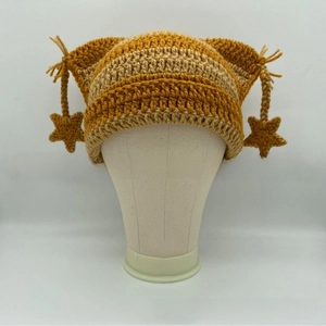 Detail of hand-knitted cat ear hat with yellow stripes and star tassel charms