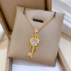 Elegant gold bow key necklace with heart zirconia pendant inside a cream gift box