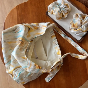 Detail of artistic marble pattern tote bag with matching scrunchies on a wooden table