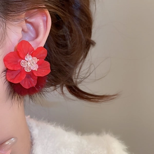 Detailed close-up of red acrylic flower earrings with fuzzy pom-poms on a model