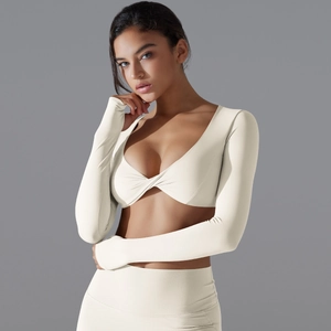 Dettaglio del set yoga crema con top a maniche lunghe a incrocio e leggings a vita alta