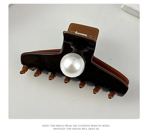Close-up of a brown hair claw clip featuring a large white pearl and polished resin finish