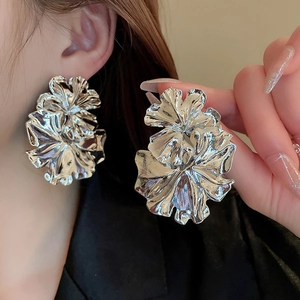 Macro shot of oversized silver fan-shaped flower earrings with irregular pleated petals