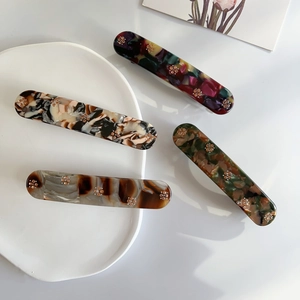 Four tortoiseshell hair clips with rhinestone flowers on a clean white tray