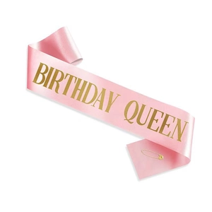 Close-up of pink satin birthday queen sash with gold foil lettering and safety pin