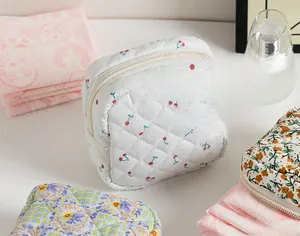 Close-up of quilted cotton pouches with cherry and floral prints featuring zipper closure