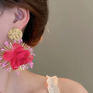 Macro shot of rose pink chiffon flower drop earrings with golden hammered studs on model