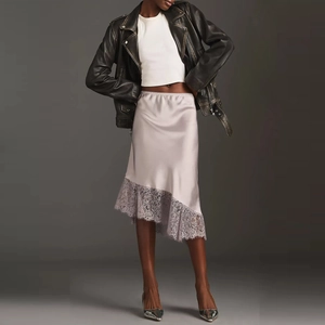 Detail of dusty pink satin midi skirt featuring delicate lace trim and asymmetric hem cut