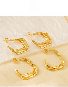 Détail de boucles d'oreilles en acier titane plaqué or 18K avec texture géométrique