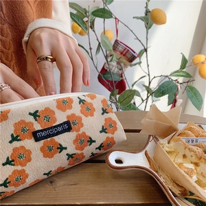 Detail of floral corduroy pencil case with zipper and label on a wooden table