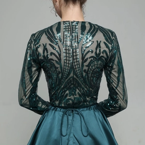 Close-up of emerald green sequin embroidery and satin texture on back of evening gown