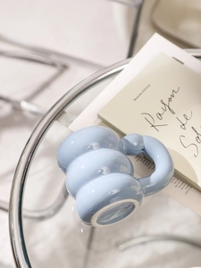 Top view of a sky blue cloud-shaped ceramic mug on a modern glass table