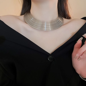 Detail of layered silver geometric choker necklace on model with soft lighting
