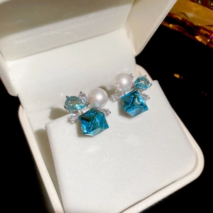 Detailed close-up of silver earrings with sea blue square crystals and white pearls