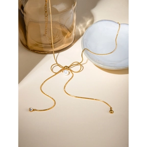 Detailed close-up of 18k gold plated bow pendant with center pearl and zircon accents