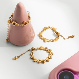 Adjustable 18K gold stainless steel rings with clover and heart charms on display