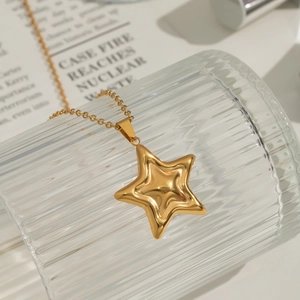 Fashionable gold star pendant necklace on a fluted glass cup with elegant lighting