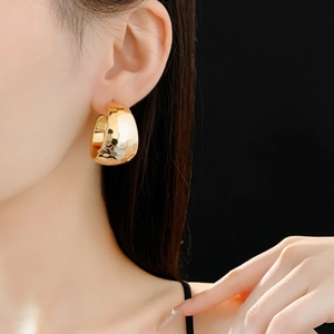 Detail of gold C-shaped chunky earrings with hammer finish texture on a model