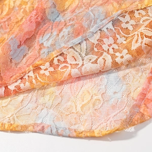 Detailed close-up of floral lace fabric featuring orange and pink patterns with fine stitching