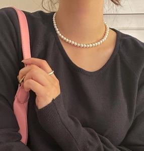 Classic 925 silver necklace featuring round 10mm cream pearls on a black knit sweater
