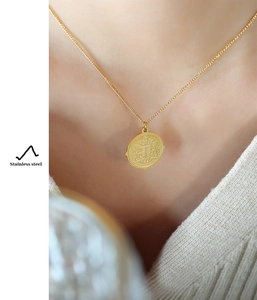 Gros plan d'un collier en acier inoxydable doré avec pendentif pièce de monnaie sur un mannequin