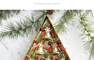Macro detail of gold Christmas bells with red bows in a triangle gift box on white snow