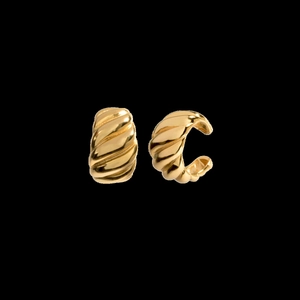Macro detail of golden ribbed croissant ear cuffs showing metallic texture and clip-on design
