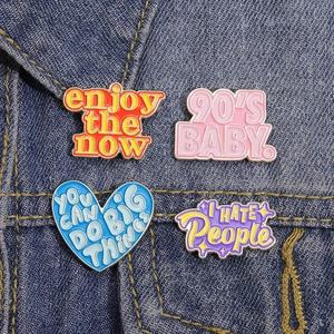 Detailed view of colorful enamel quote pins displayed on blue denim fabric