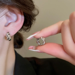 Macro detail of silver twisted hoop earrings with elegant textured metal finish