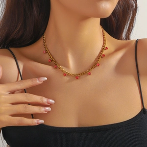Close-up of a gold-plated stainless steel chain necklace with red heart pendants on a model