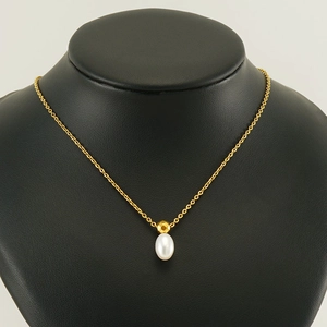 Elegant gold stainless steel necklace with teardrop pearl and faceted bead on black bust