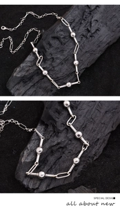 Detail of silver spherical bead necklace with oval links on a dark textured background