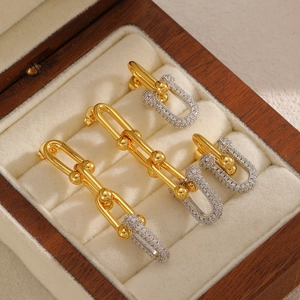 Elegant U-shaped gold stud earrings with diamonds on a wooden jewelry box display