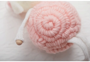 Detail of pink and white wool felt handmade ornament with macro texture and wooden beads