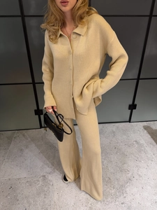 Detail of light yellow knit cardigan with buttons and matching high-waisted trousers