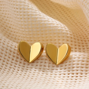 Macro shot of gold heart button earrings with faceted metallic surface and polished finish