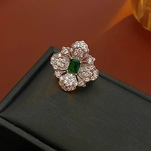 Detail of flower ring with emerald-cut green stone and sparkling cubic zirconia stones