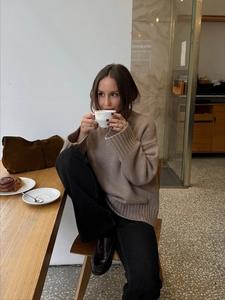 Close-up of oatmeal knit sweater texture and relaxed silhouette in cafe setting