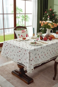 Detailed view of cream cotton tablecloth with festive berry patterns and tassel fringe