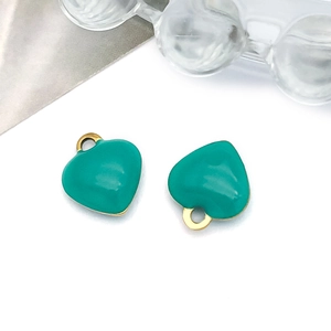 Detail of heart-shaped teal enamel pendant with gold trim and top hanging hole for jewelry