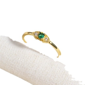 18K gold-plated ring with emerald-green cubic zirconia stone on beige fabric