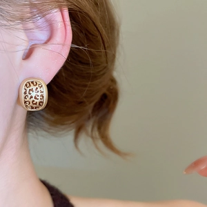 Macro side view of model wearing leopard print oval earrings in gold finish